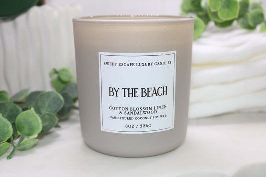 By The Beach candle by Sweet Escape Luxury Candles with notes of cotton blossom, linen, and sandalwood, evoking a tranquil seaside atmosphere.