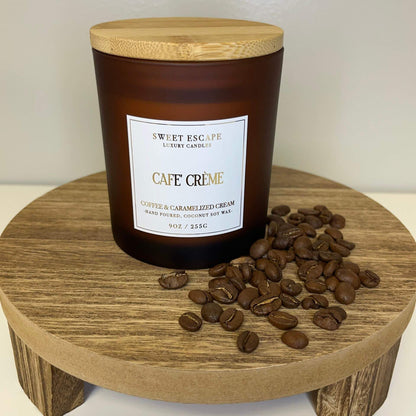 Cafe Creme' 9oz hand-poured coconut soy wax candle with fresh coffee bean and caramelized cream fragrance on a wooden stand with coffee beans.