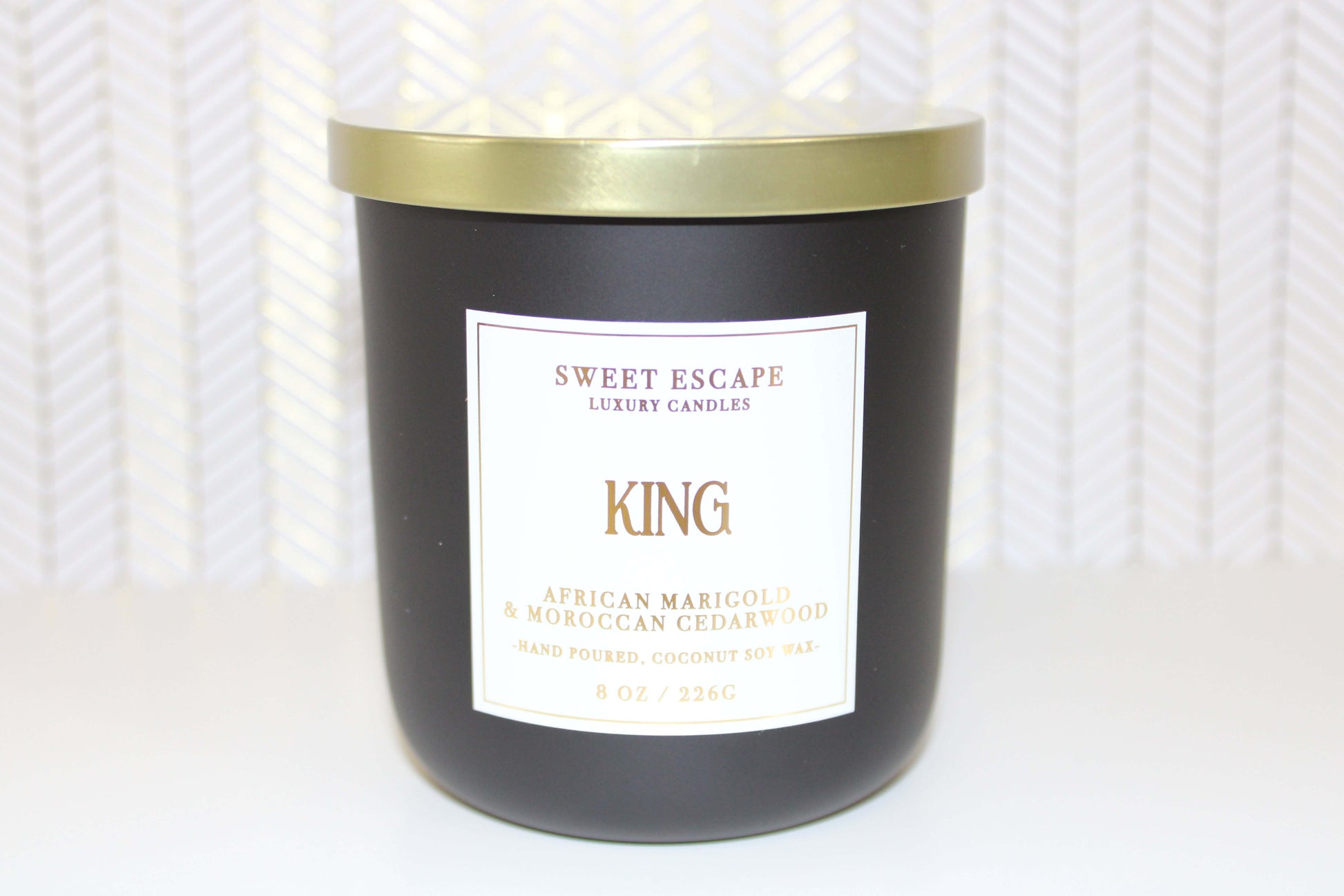 King Candle by Sweet Escape Luxury Candles in a black jar with gold lid, featuring a rich blend of African marigold, bergamot, and Moroccan cedarwood scents